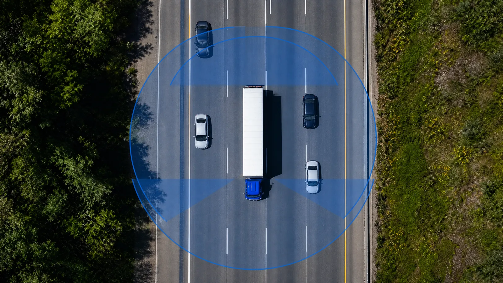 Top-down view of a truck on a motorway with its 360-degree camera coverage zone highlighted